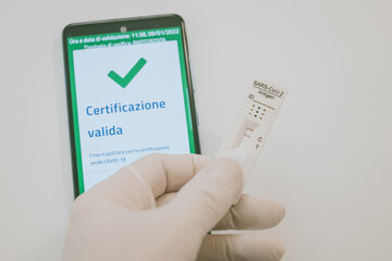 Closeup view of gloved hand with SARS-CoV-2 rapid antigen test nasal, phone with green digital...