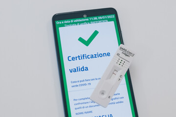 Closeup view of gloved hand with SARS-CoV-2 rapid antigen test nasal, phone with green digital...