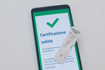 Closeup view of gloved hand with SARS-CoV-2 rapid antigen test nasal and phone with green digital...