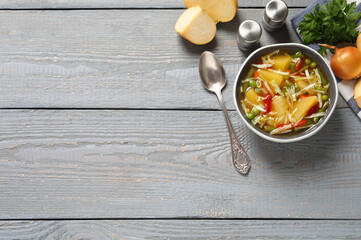 Bowl of delicious turnip soup served on grey wooden table, flat lay. Space for text