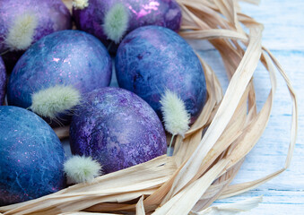 Happy Easter festive card. Chicken eggs in a straw nest on a wooden background. Natural dye karkade tea. Zero waste concept. 