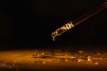 cosmetic pipette with cosmetic oil, perfume, essence, on a black background, gold-colored liquid. - obrazy, fototapety, plakaty