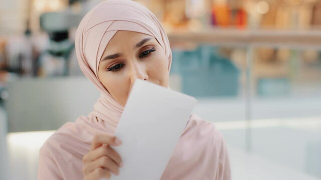 Close-up young muslim woman in hijab opens paper letter reads bad news shocked feels disappointed sad arab girl finds out about failed exams getting fired from job bank loan denial notice bankruptcy