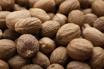 Heap of nutmeg seeds as background, closeup