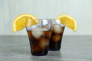 Delicious cocktails with orange and ice balls on grey table