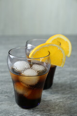 Delicious cocktails with orange and ice balls on grey table