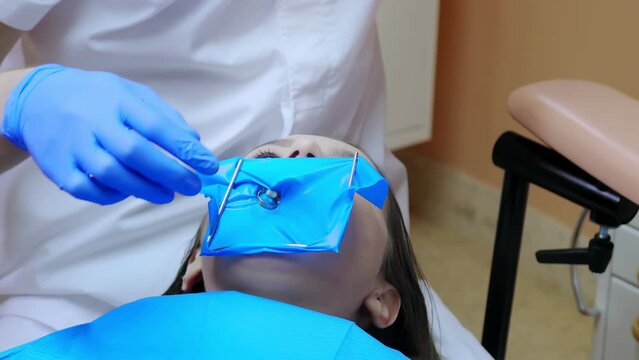 A dentist putting cofferdam for treats teeth. Dental equipment.