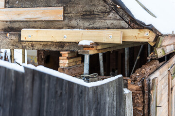 An old, historic wooden house is being restored in winter day