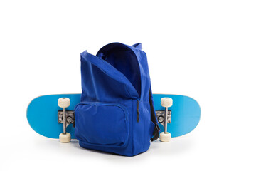 Blue open backpack next to skateboard on white background, back to school