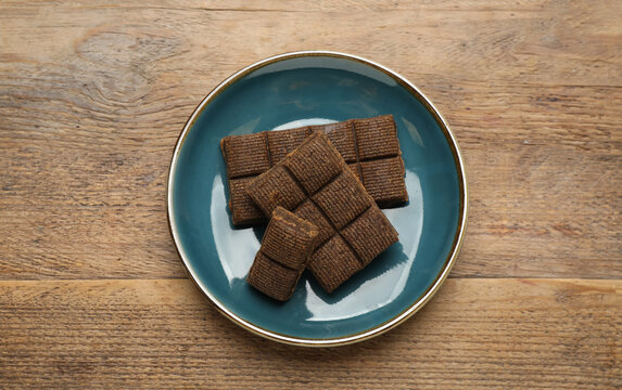 Blue plate with delicious and healthy hematogen on wooden table, top view