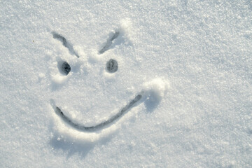 Face of an insidious, angry, smiley, painted on the snow on a sunny winter day. Copy space. Top view.