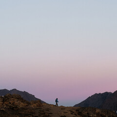 Silhouette adventure girl hiking on mountains during sunset in Alaska with colorful sky on vacation and working remotely
