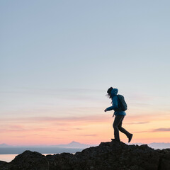 Silhouette adventure girl hiking on mountains during sunset in Alaska with colorful sky on vacation and working remotely - obrazy, fototapety, plakaty