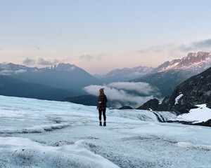 Adventure Girl hiking climbing exploring on blue glacier in Valdez Alaska with mountains in background at sunset. Amazing colors