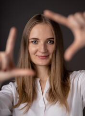 Fototapeta premium Young woman smiling and showing frame with her fingers.