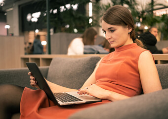 Young woman with laptop sitting in cafe.