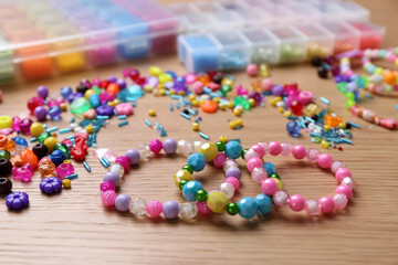 Beautiful handmade beaded bracelets and supplies on wooden table