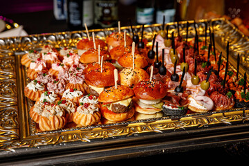 Small burgers and other snacks on the tray. Party catering.