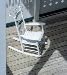 A single white wooden rocking chair shot from above on a wooden porch