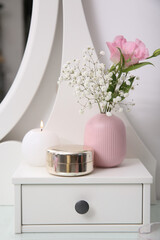Beautiful flowers in vase and decor on drawer of white dressing table