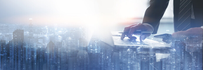 Business finance and investment concept. Double exposure of businessman working on laptop computer and the city, office buildings for business and financial technology background