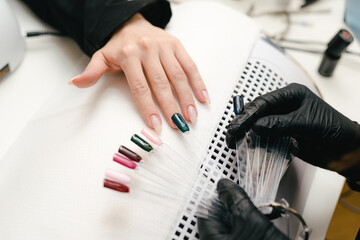 Choice of manicure color. A girl in a beauty salon takes care of her nails.