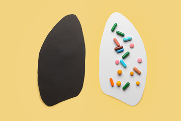 Paper human lungs with pills on color background