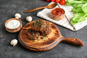 Board with tasty lentil cutlets on dark background