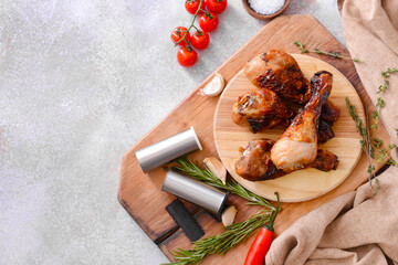 Board with tasty cooked chicken drumsticks on grunge background