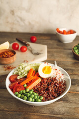 Healthy quinoa bowl with egg on wooden table