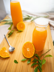 Bottles of fresh orange juice with sliced orange on wooden background