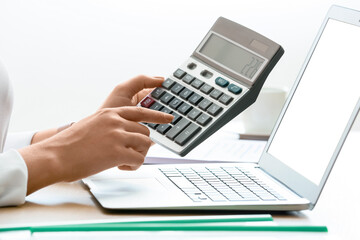 Businesswoman working with calculator and laptop at desk in office, closeup