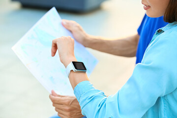 Couple of young tourists with map and smartwatch outdoors