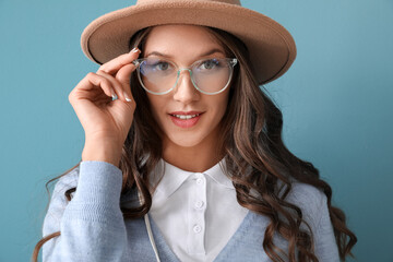Portrait of young woman wearing stylish eyeglasses on blue background