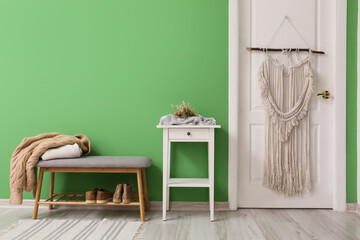 Interior of modern hallway with table and pouf near green wall