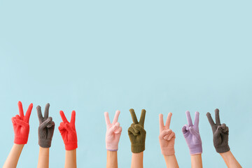 Women in warm gloves showing victory gesture on blue background