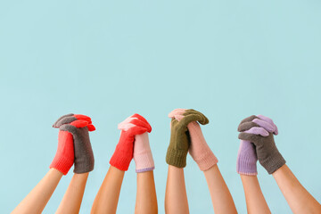 Women in warm gloves holding hands on blue background