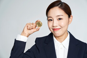 Young business woman holding bitcoin and posing with studio shot
