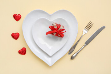 Beautiful table setting and gift for Valentine's Day on yellow background