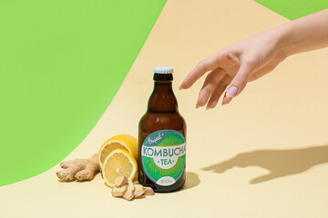Female hand with fresh kombucha on color background