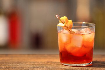 Glass of tasty Negroni cocktail on table against blurred background