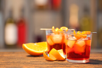Glasses of tasty Negroni cocktail on table against blurred background