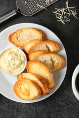 Plate of tasty croutons with sauce on black background