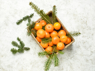 Fototapeta na wymiar Box with tasty tangerines and fir branches on light background