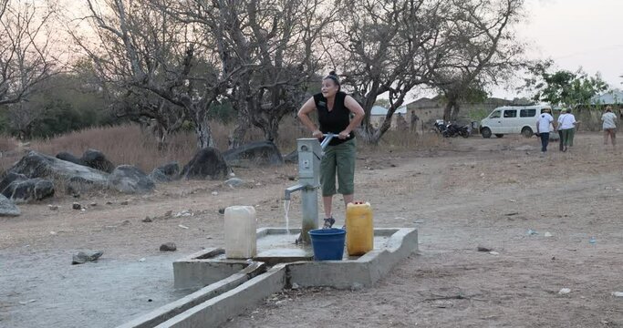 Sherri pumping fresh water borehole well northern Ghana. Remote northern Savannah region. Wells or water pumps placed near village as only source of clean water for drinking, cooking and washing.