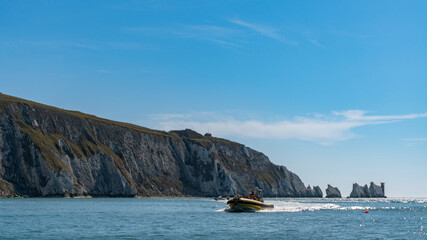 Far away view of the Needles and a boat, in Alum Bay, Isle of Wight, United Kingdom