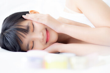 Obraz na płótnie Canvas Beautiful of young asian woman smiling and lying on bed at bedroom, beauty of girl touch cheek with hygiene and healthy, cream and lotion, cosmetic and makeup, skin care and lifestyles concepts.