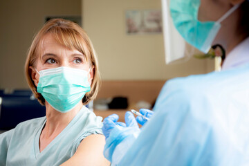 Doctor woman holding syringe and injection vaccine patient elderly in face mask for prevention coronavirus at hospital, vaccination for pandemic of senior, infection and immunization, medical concept.