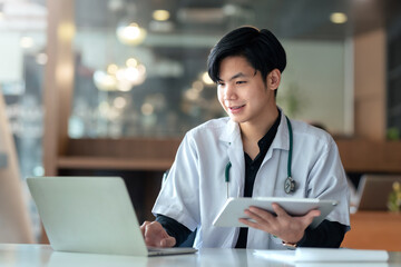 Asian male internship doctor sitting using laptop computer in the office.