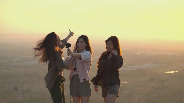 Friend group of Asian young women having fun and enjoy on a summer vacation vlogging from the mountain in nature during sunset. Females Lifestyle, blogger travel